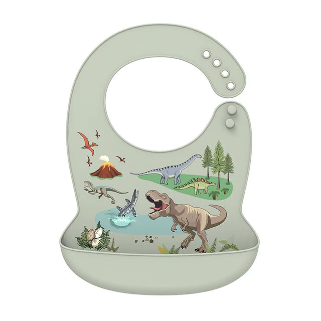Adjustable, waterproof silicone baby bib in sage green with colorful dinosaur and volcano print, featuring a deep catch-all pocket.