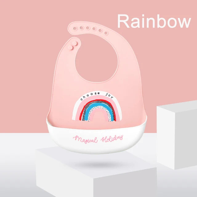 Pink silicone baby bib with rainbow design, adjustable neck, and deep food-catching pocket.