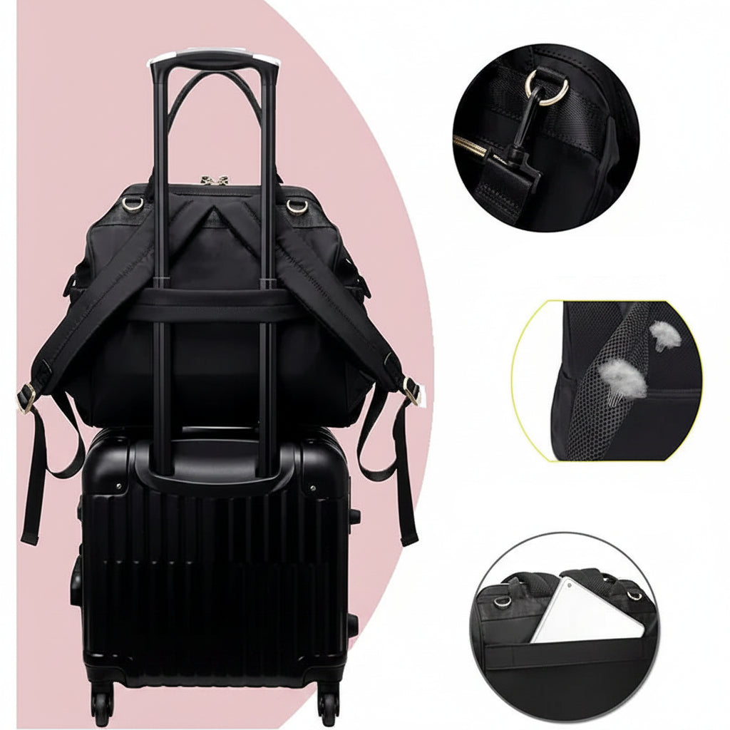 Black polyester diaper backpack with padded straps and luggage strap, shown on a suitcase.