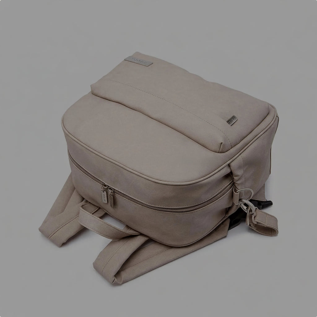 Beige waterproof diaper backpack with spill-proof, stain-resistant lining and front zipper pocket.