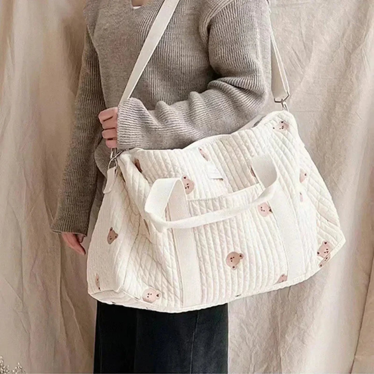 Quilted white cotton diaper bag with cute bear print, shoulder strap, and top handles.