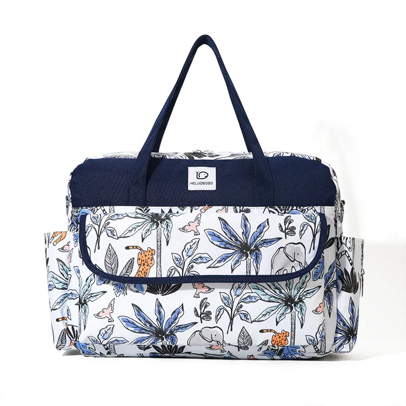 White and navy Oxford fabric diaper bag with jungle animal and palm tree print, top handles, and side pockets.