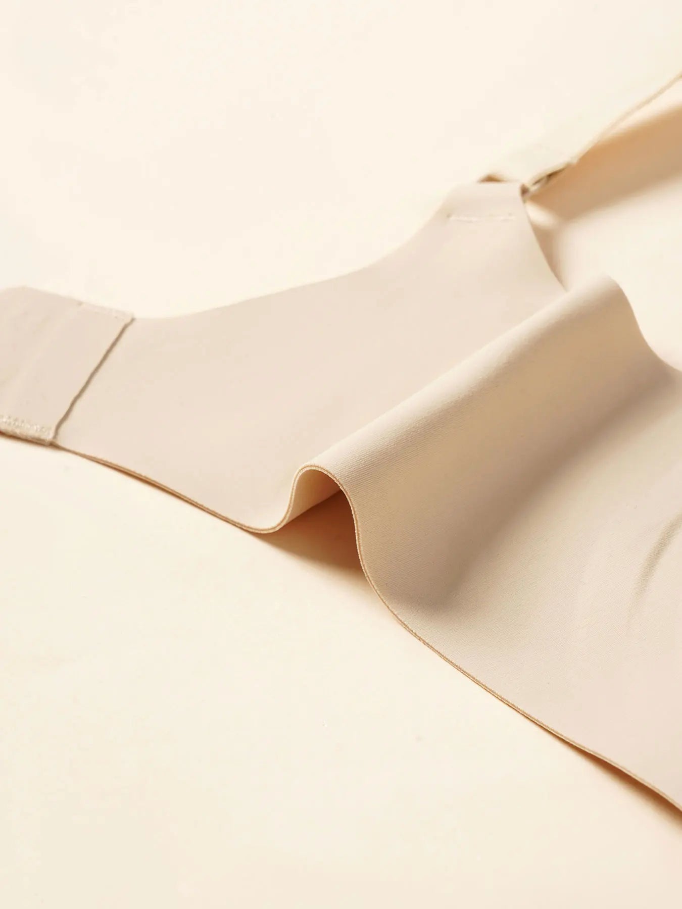 Beige wireless V-neck nursing bra made of soft, flexible nylon-spandex blend with removable pads.